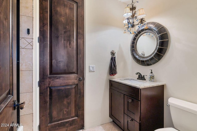 bathroom with vanity, tile patterned flooring, toilet, and an inviting chandelier