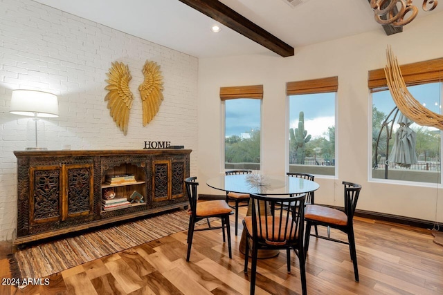 dining space with brick wall, hardwood / wood-style floors, and beamed ceiling