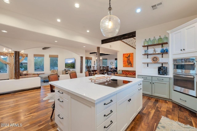 kitchen featuring a center island, a breakfast bar, dark hardwood / wood-style flooring, white cabinetry, and decorative light fixtures