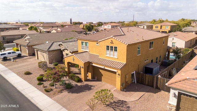 view of front of home with stucco siding, a tile roof, decorative driveway, fence, and a residential view