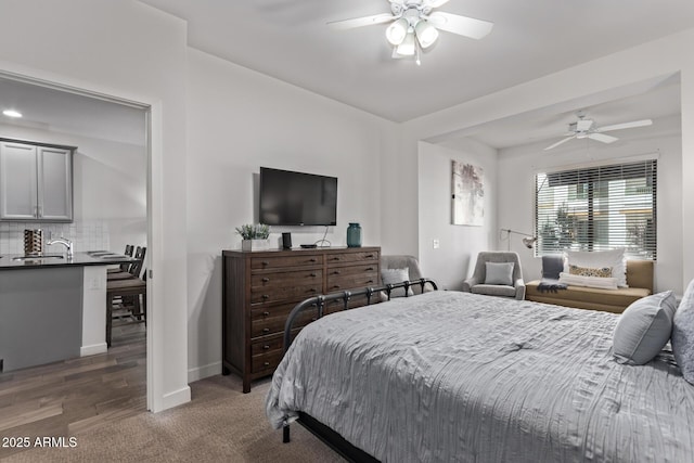 carpeted bedroom featuring a sink, ceiling fan, and baseboards