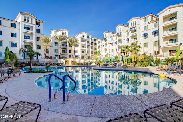 community pool with a patio area and fence