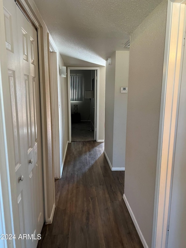 hall featuring a textured ceiling and dark hardwood / wood-style floors