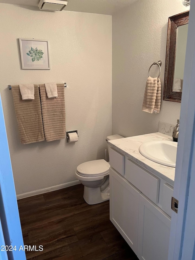 bathroom with toilet, vanity, and hardwood / wood-style flooring