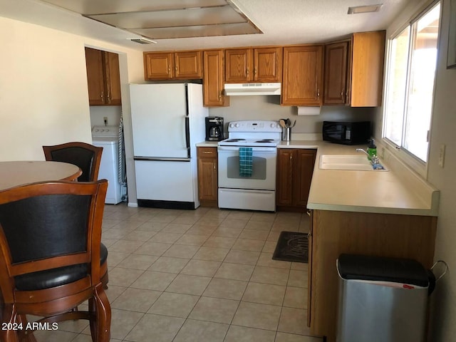 kitchen with light tile patterned floors, white appliances, sink, and washer / clothes dryer