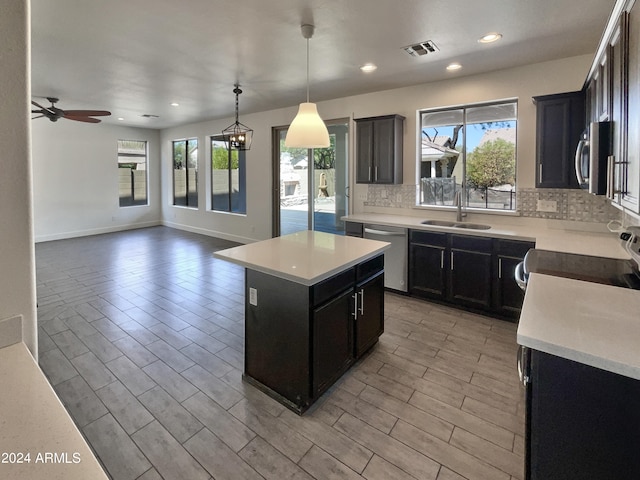 kitchen with ceiling fan with notable chandelier, pendant lighting, stainless steel appliances, a center island, and sink