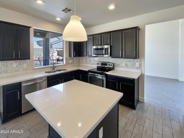 kitchen with light hardwood / wood-style flooring, stainless steel appliances, hanging light fixtures, and sink