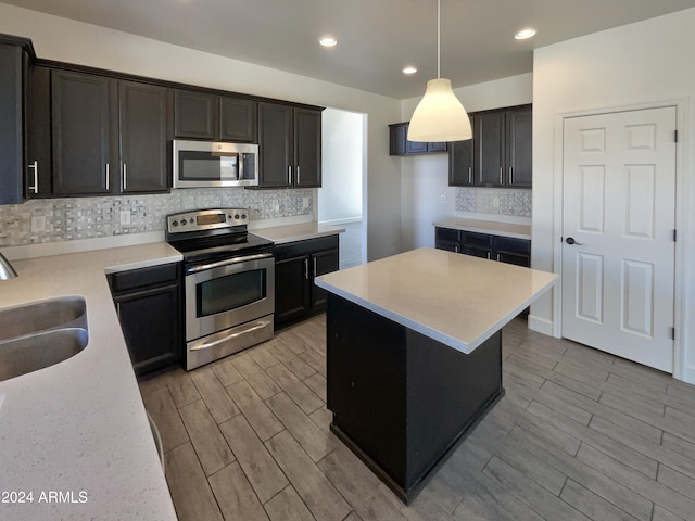 kitchen featuring appliances with stainless steel finishes, light wood-type flooring, sink, and decorative light fixtures