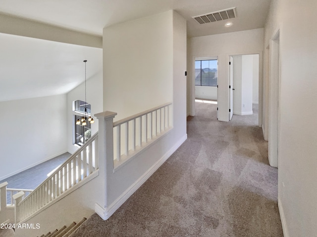 hallway with light carpet and an inviting chandelier