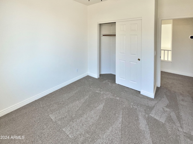 unfurnished bedroom featuring dark carpet and a closet