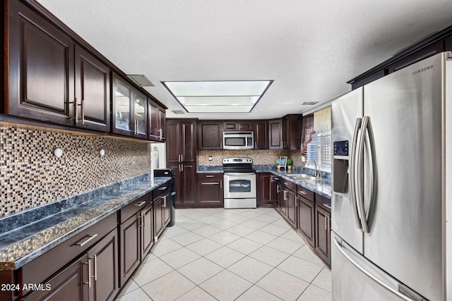 kitchen with appliances with stainless steel finishes, sink, dark brown cabinets, and light tile patterned floors