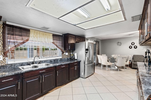 kitchen featuring dark brown cabinets, sink, stainless steel fridge, light tile patterned floors, and a textured ceiling