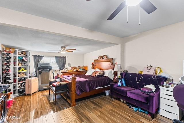 bedroom with a textured ceiling, wood-type flooring, and ceiling fan