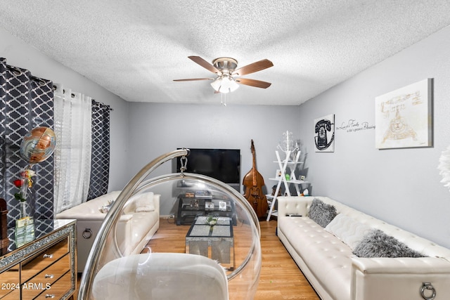 living room featuring light hardwood / wood-style flooring, a textured ceiling, and ceiling fan