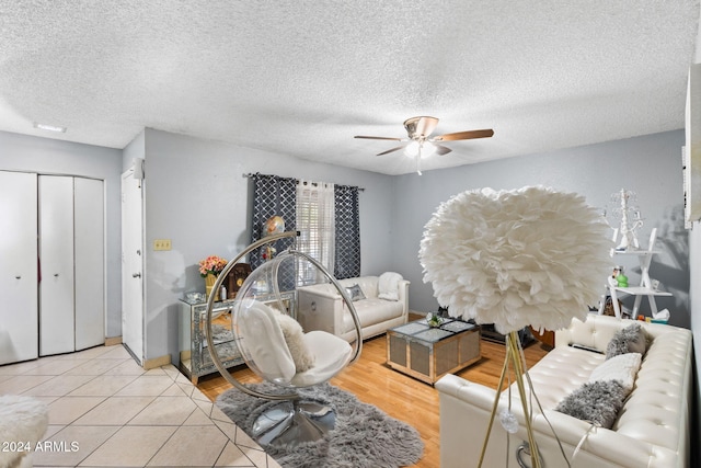 living room featuring ceiling fan, a textured ceiling, and light tile patterned floors