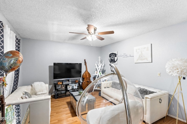 living room featuring a textured ceiling, light wood-type flooring, and ceiling fan