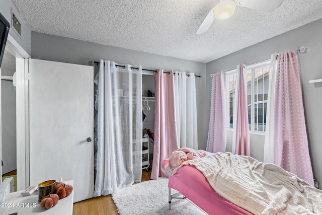 bedroom with light hardwood / wood-style floors, a textured ceiling, and ceiling fan