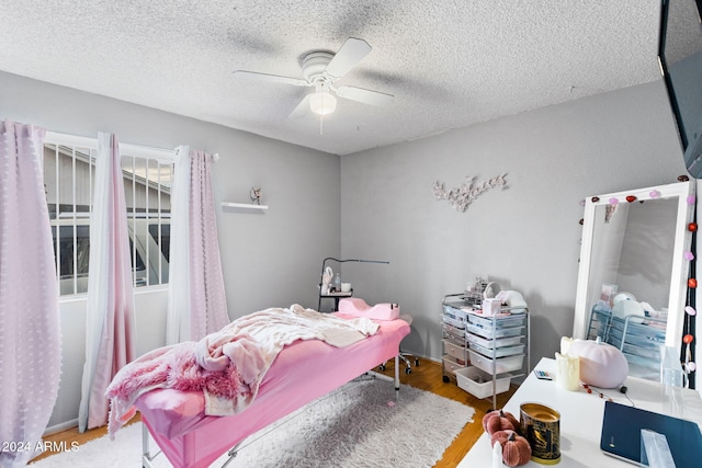 bedroom with a textured ceiling, hardwood / wood-style flooring, and ceiling fan