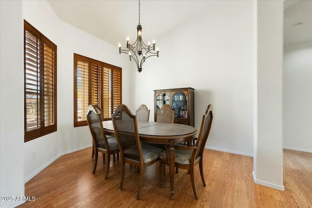 dining space with an inviting chandelier, vaulted ceiling, and hardwood / wood-style floors