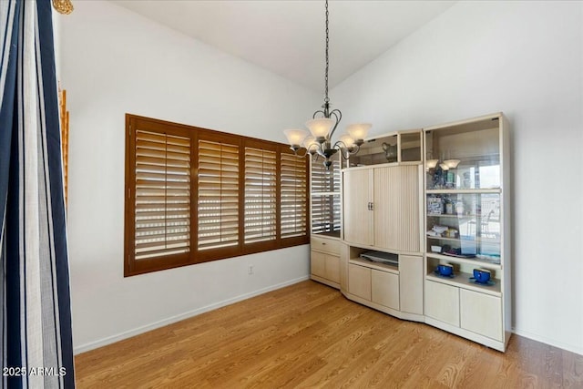 interior space featuring light hardwood / wood-style flooring, a notable chandelier, and vaulted ceiling