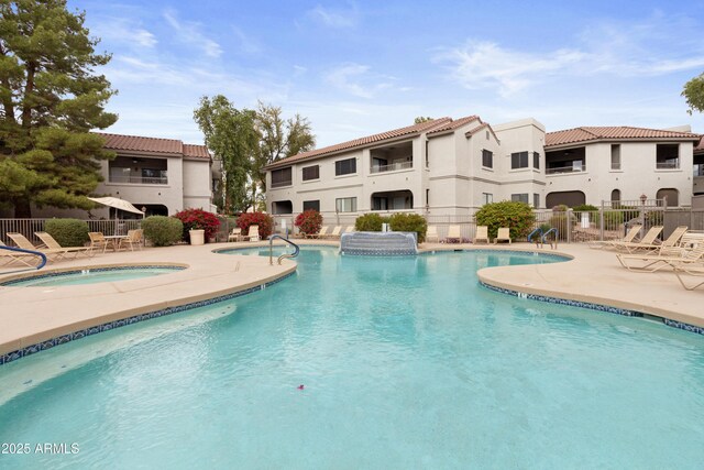 pool with a community hot tub, fence, and a patio