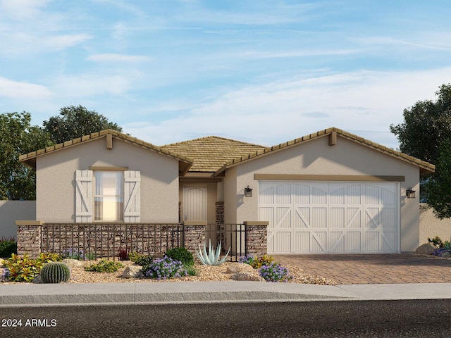 view of front of house with decorative driveway, an attached garage, a tile roof, and stucco siding