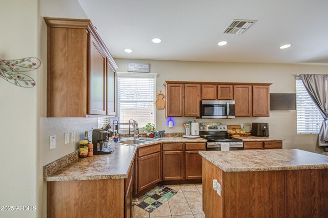 kitchen featuring stainless steel appliances, a sink, light tile patterned floors, brown cabinets, and recessed lighting