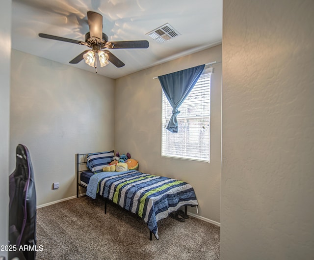 carpeted bedroom featuring ceiling fan, baseboards, and a textured wall