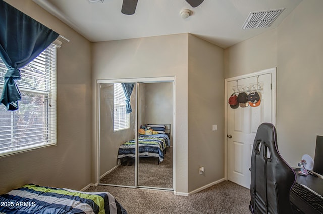 carpeted bedroom featuring multiple windows, ceiling fan, baseboards, and a closet