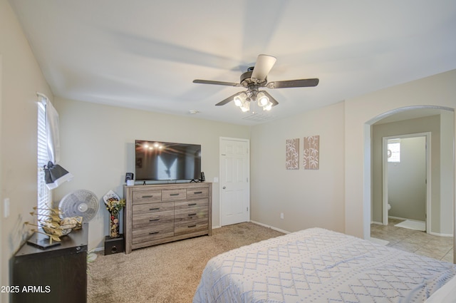 bedroom featuring arched walkways, baseboards, ceiling fan, and light colored carpet