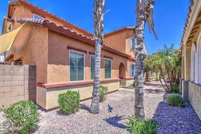 view of property exterior with stucco siding and fence