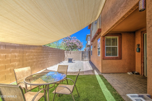 view of patio with a fenced backyard, outdoor dining space, and a gate