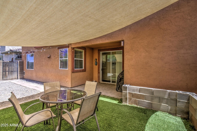 view of patio with outdoor dining space, fence, and a gate