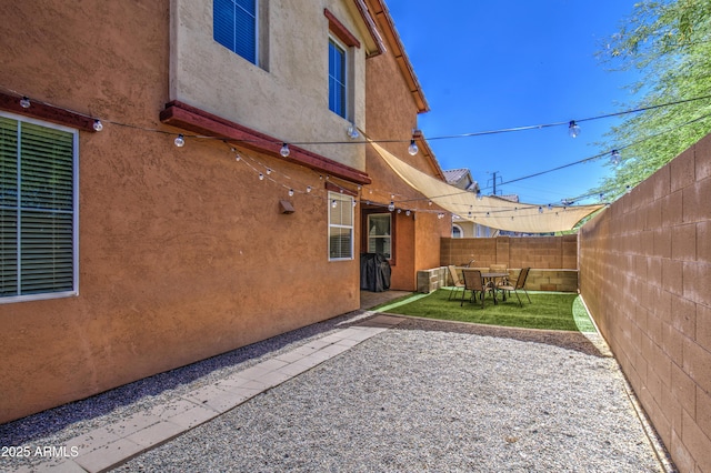 rear view of property with stucco siding, a fenced backyard, a patio area, and outdoor dining space