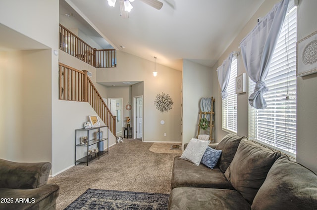 carpeted living area with stairway, vaulted ceiling, a ceiling fan, and baseboards