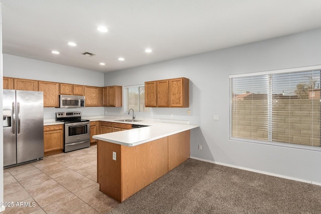 kitchen featuring sink, light tile patterned flooring, kitchen peninsula, and appliances with stainless steel finishes