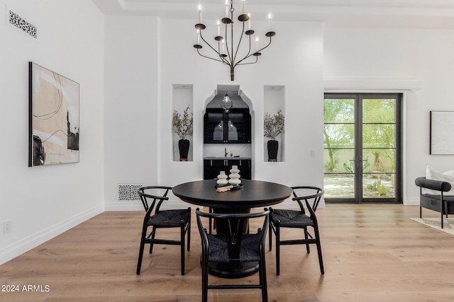 dining room with light hardwood / wood-style floors, a high ceiling, and a notable chandelier