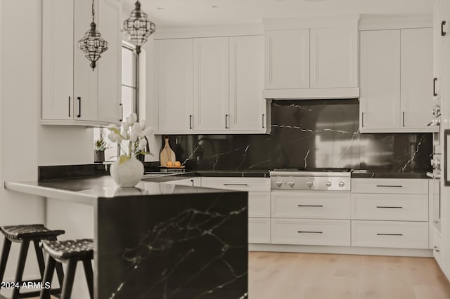 kitchen featuring white cabinets, decorative light fixtures, decorative backsplash, stainless steel gas cooktop, and light hardwood / wood-style flooring