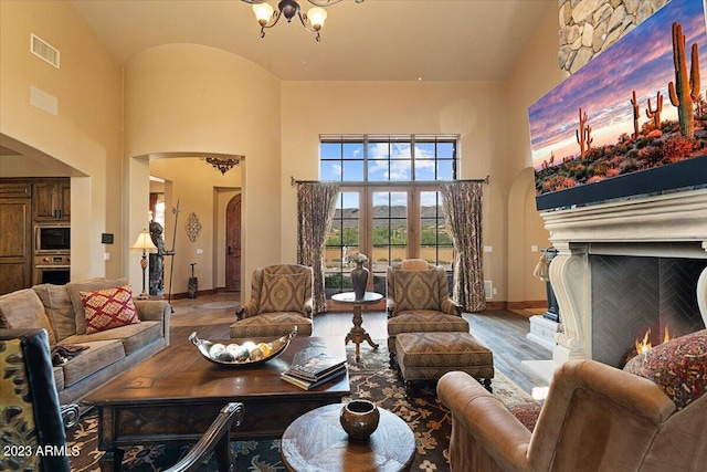 living room featuring a chandelier, high vaulted ceiling, and wood-type flooring