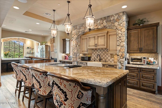 kitchen with a large island, sink, stainless steel gas stovetop, and light wood-type flooring