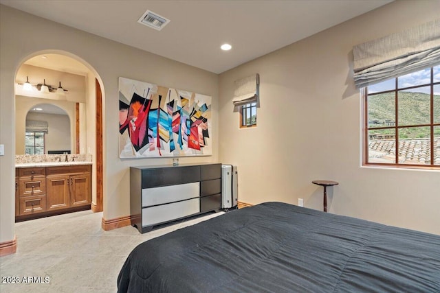 carpeted bedroom with ensuite bathroom and sink