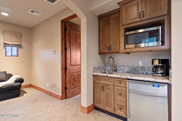 kitchen featuring appliances with stainless steel finishes, sink, light stone counters, and light tile patterned floors