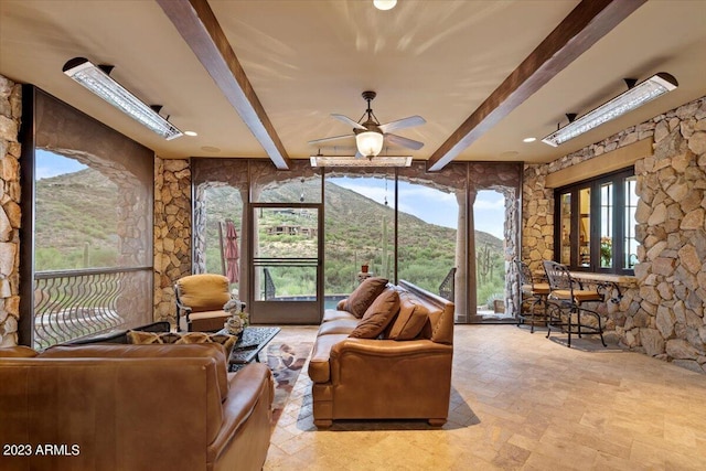 living room with a mountain view, beamed ceiling, and ceiling fan