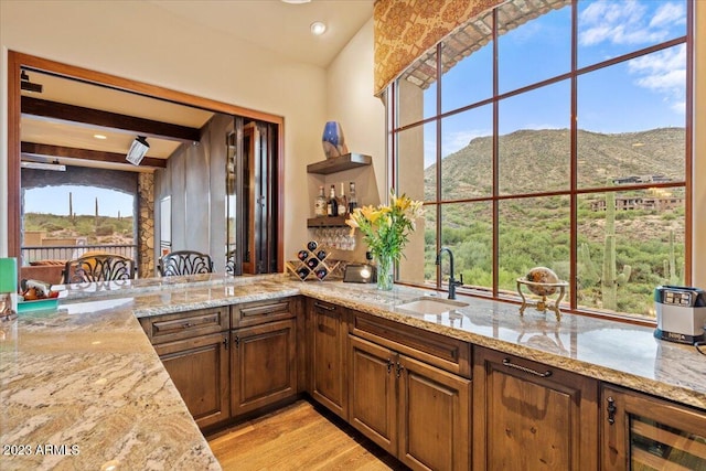 kitchen with a mountain view, light stone countertops, sink, and light wood-type flooring