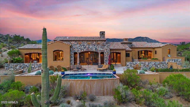 back house at dusk with a patio area