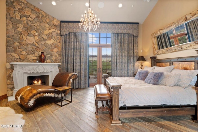 bedroom with high vaulted ceiling, access to outside, and hardwood / wood-style floors