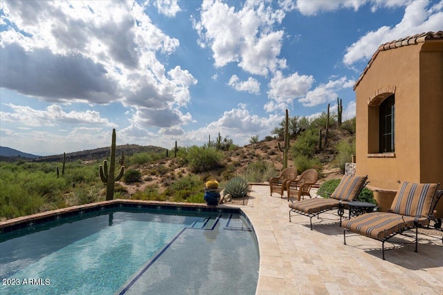 view of swimming pool with a patio area and a mountain view