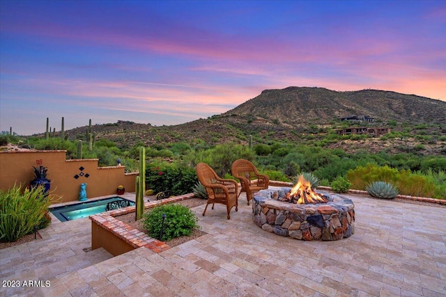 patio terrace at dusk featuring a mountain view and a fire pit