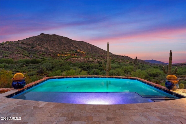 pool at dusk featuring a mountain view