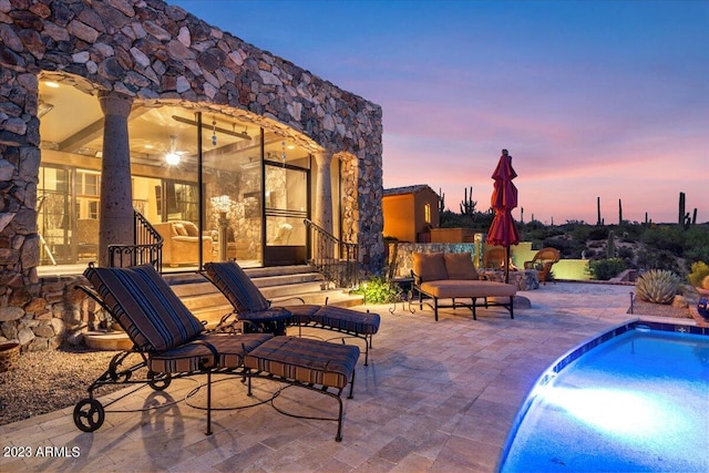 pool at dusk featuring a patio area